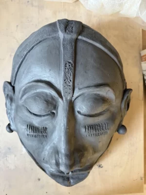 Tonmaske mit geschlossenen Augen und strukturierten Verzierungen